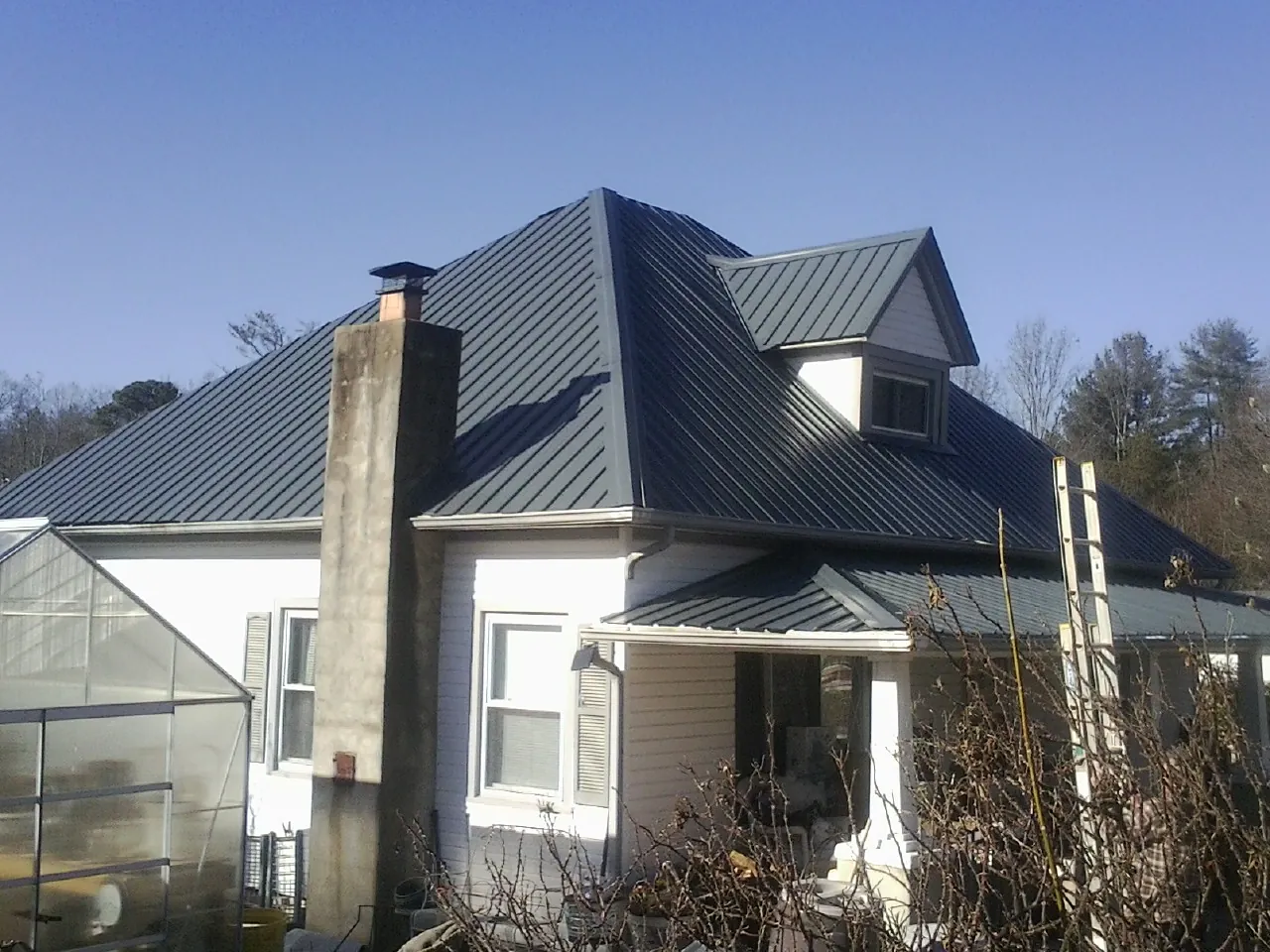 Dark blue standing seam metal roof on a white farmhouse with dormer — Slate & Tile Roof Repair by Roofing Brothers in Orrs Island