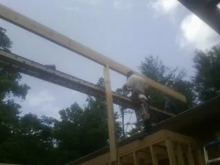 Carpenter setting a ridge beam over a new addition frame — Ice Dam Removal by Roofing Brothers in Orrs Island