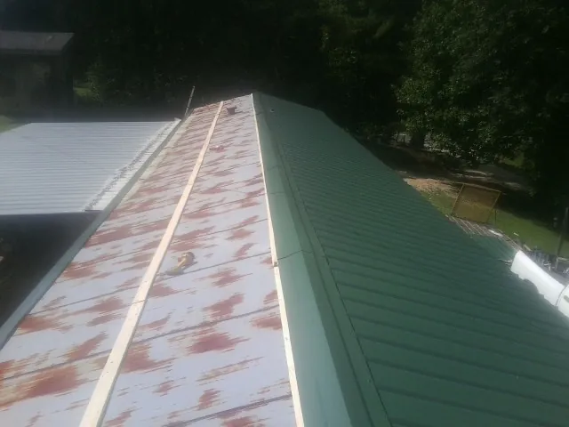 Old rusted panels beside newly installed green metal roofing — Wind Damage Roof Repair by Roofing Brothers in Orrs Island