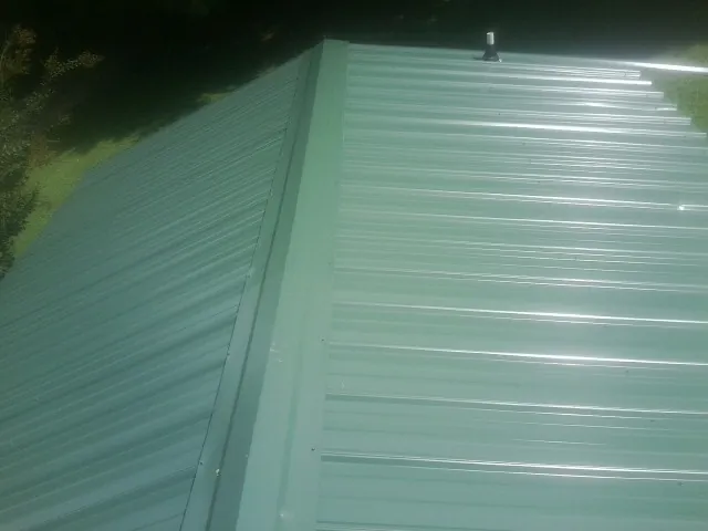 New green metal panels meeting at the ridge of a roof — Flat Roof Repair work by our crew in Orrs Island