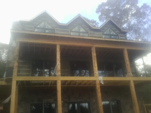Dormers and porch framing on a large log home under construction — Roof Coating work by our crew in Orrs Island