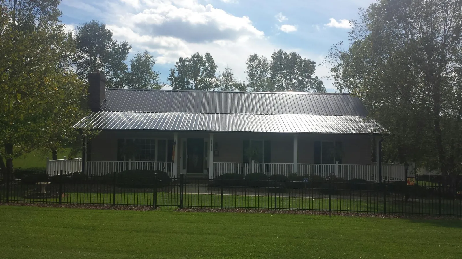 Gray metal roof on a brick ranch with a full width front porch — Gutter Guard Installation work by our crew in Orrs Island