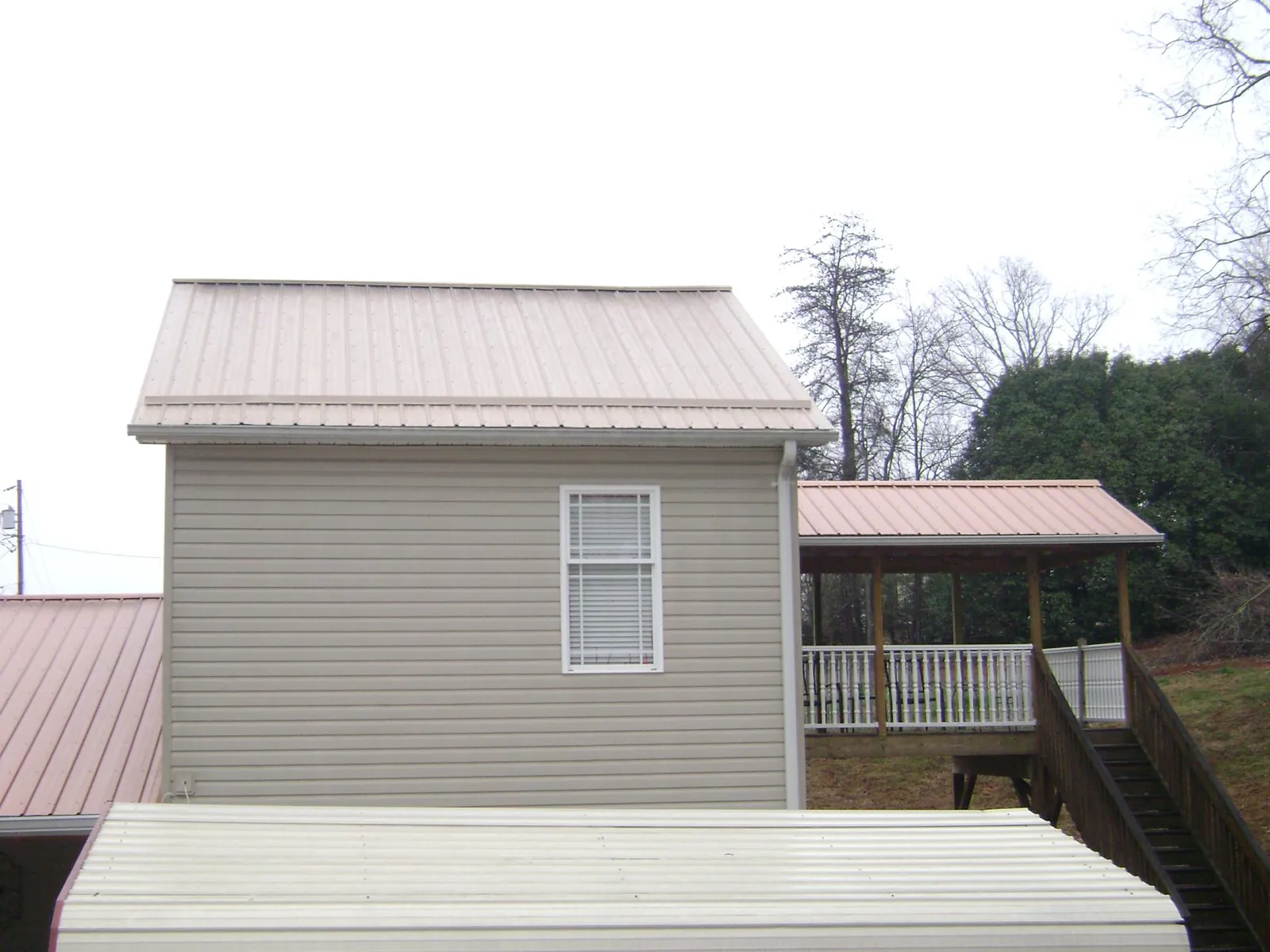 Tan metal roofs on a two story addition and attached porch, from a Roof Replacement job in Orrs Island