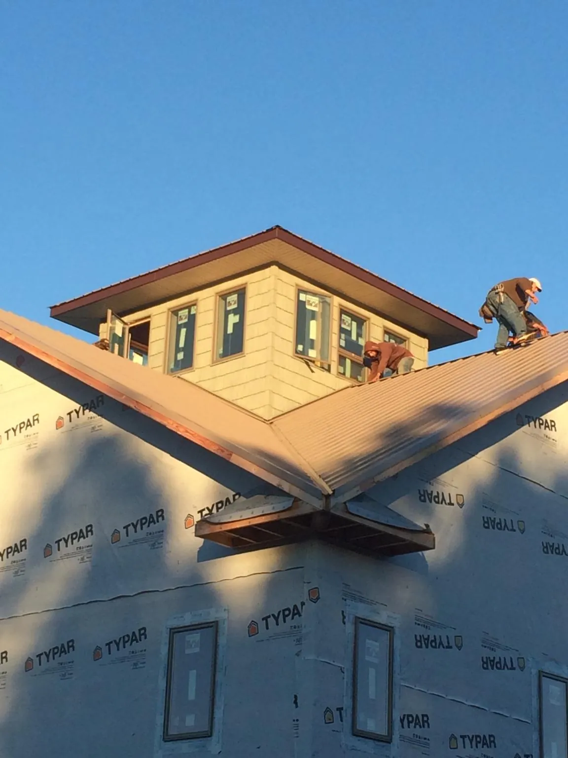 Roofers working around a rooftop cupola on a new metal roof at sunset — Roof Waterproofing in Orrs Island by Roofing Brothers